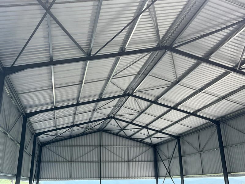Interior view of a CSI prefab steel structure looking up at the pitched roof sheeting, painted portal frames, purlins and cross-bracing